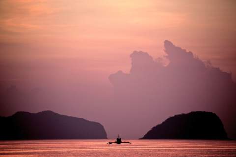 Red sunset views of traditional boat surrounded by islands