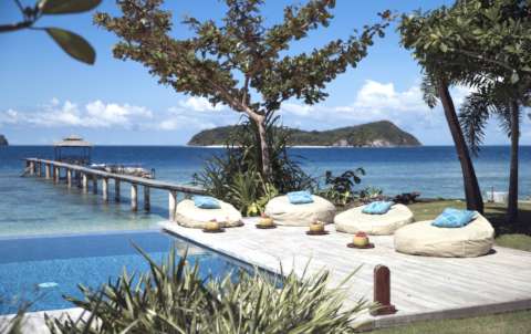 bean bags next to a pool with fresh coconut drinks