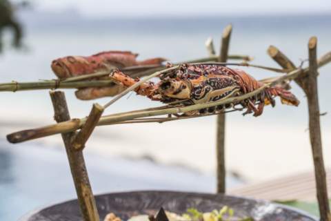 lobster and fish being cooked above an open fire